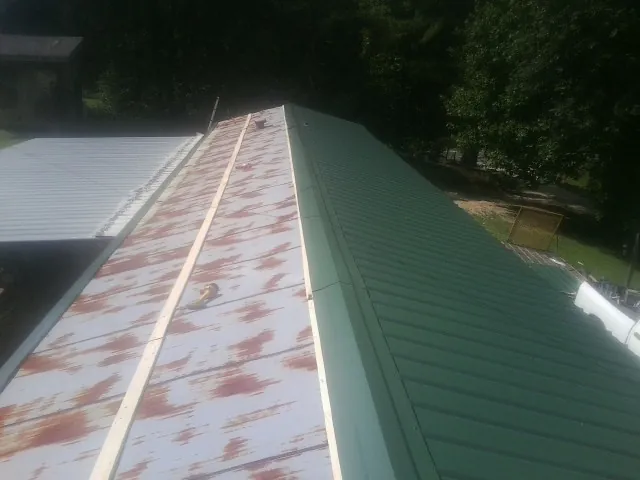 Old rusted panels beside newly installed green metal roofing — Wind Damage Roof Repair by Roofing Brothers in Panama City Beach
