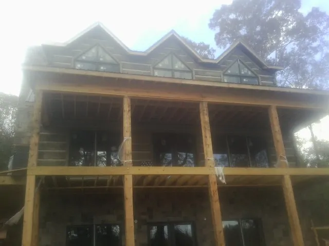 Dormers and porch framing on a large log home under construction — Roof Coating work by our crew in Panama City Beach
