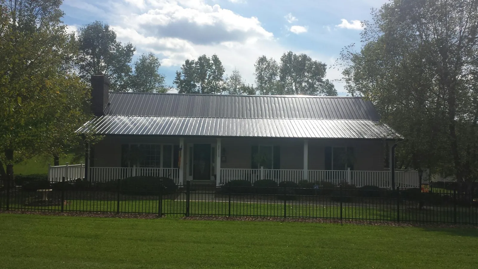 Gray metal roof on a brick ranch with a full width front porch — Gutter Guard Installation work by our crew in Panama City Beach
