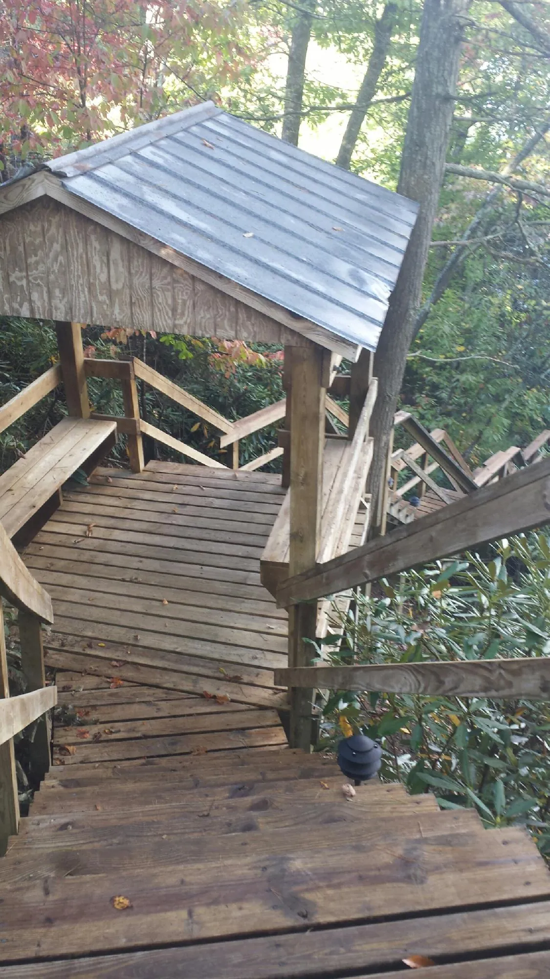 Metal roofed shelter over wooden steps on a wooded walkway — Skylight Repair & Installation work by our crew in Panama City Beach
