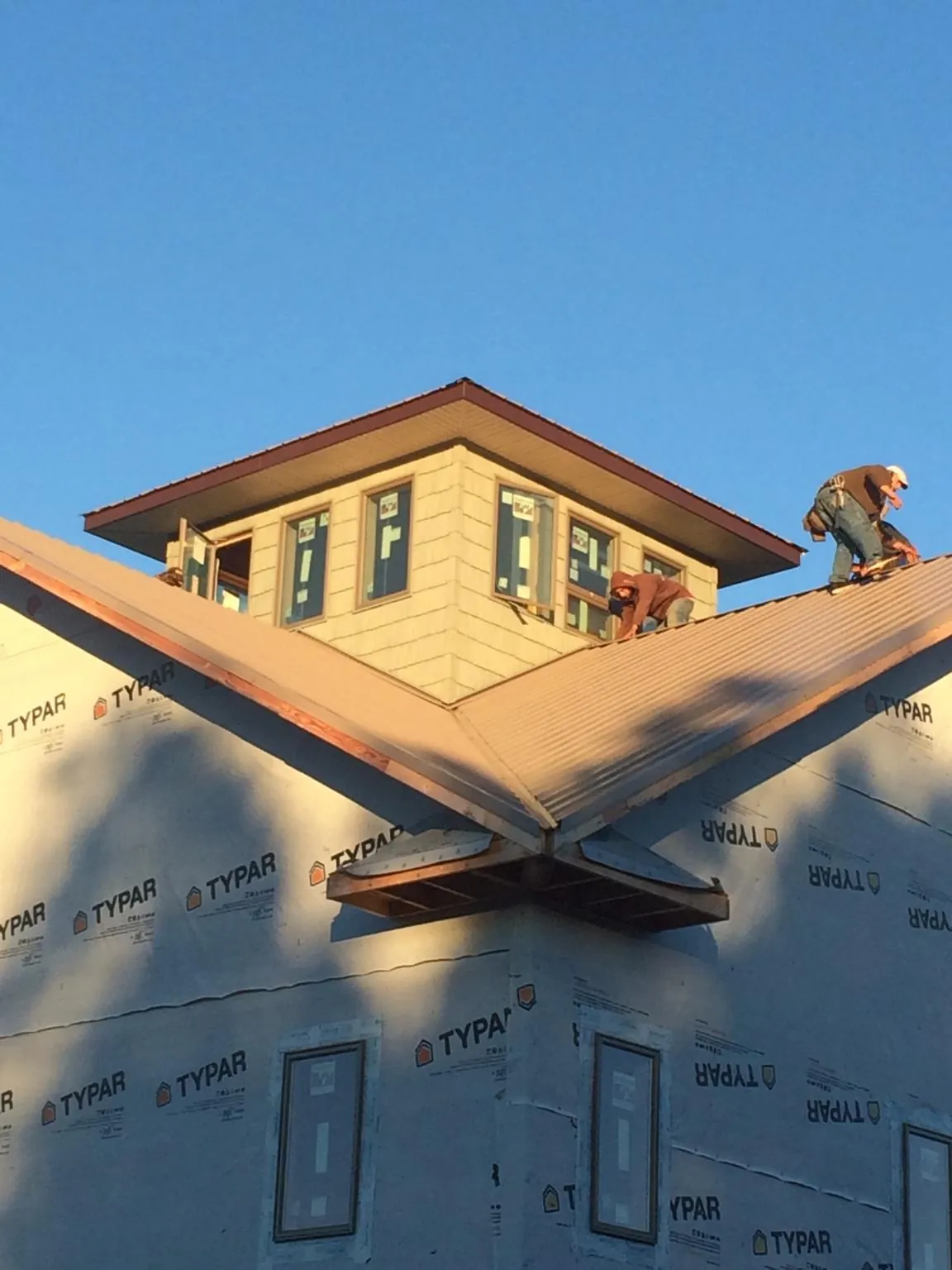 Roofers working around a rooftop cupola on a new metal roof at sunset — Roof Waterproofing in Panama City Beach by Roofing Brothers